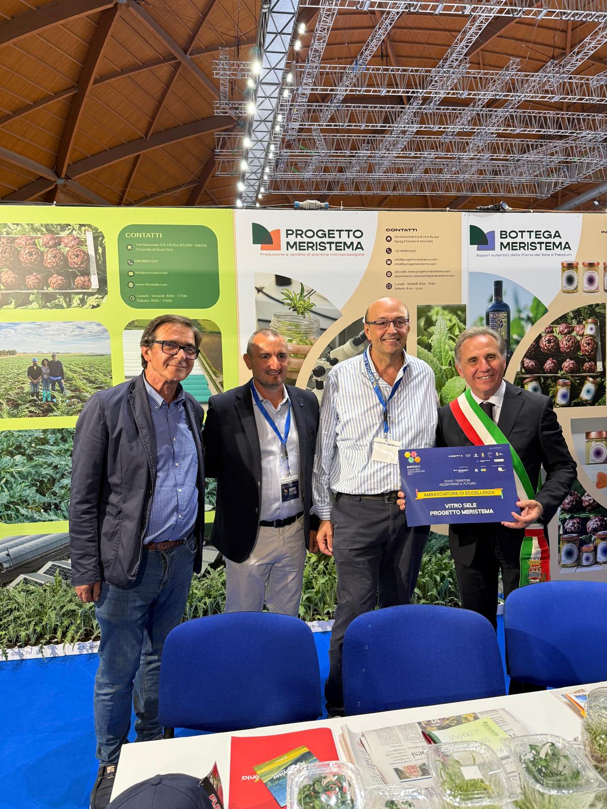 quattro persone che sorridono, una delle quali mantiene un premio con scritto "ambasciatori di eccellenza"