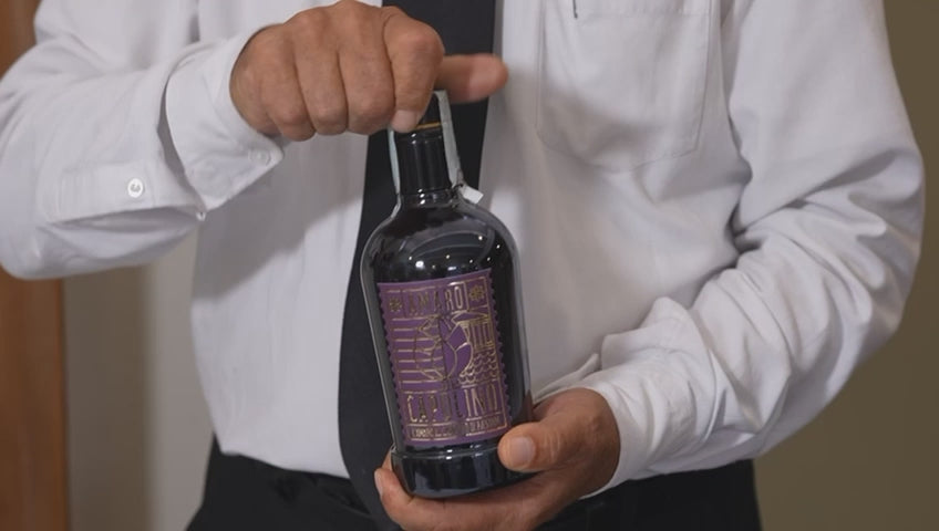 video che mostra l'amaro versato in un bicchiere da un sommelier con camicia bianca e cravatta nera.